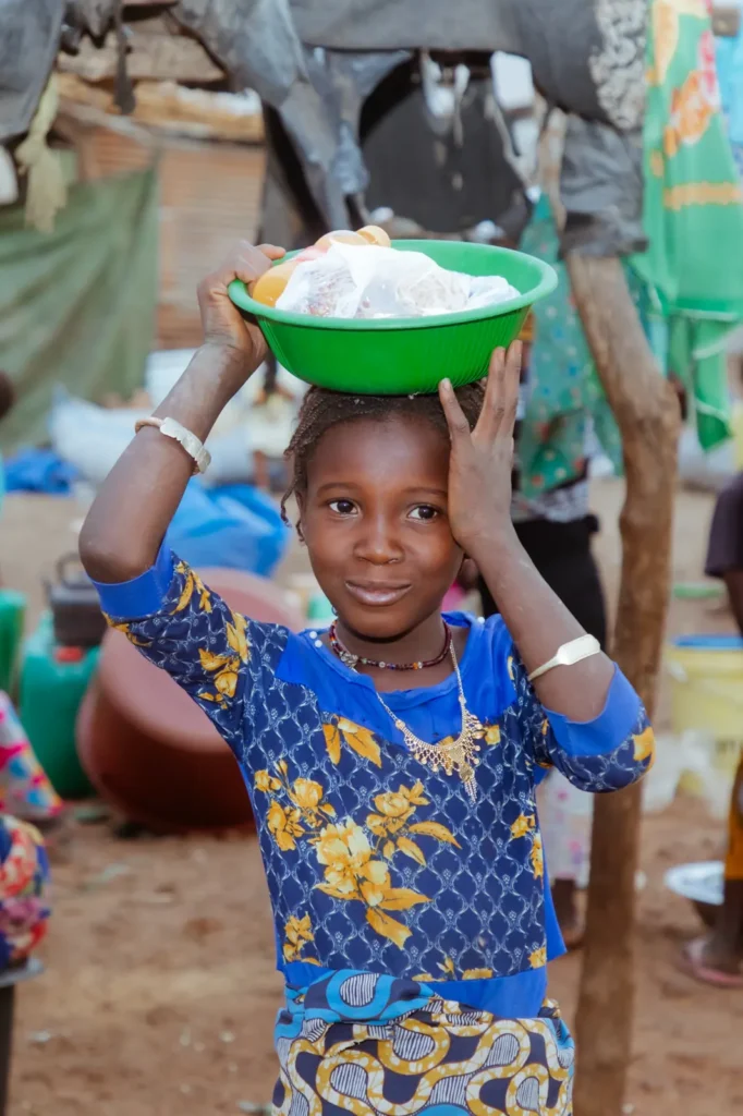 Une jeune fille porte sur la tête le repas distribué à sa famille